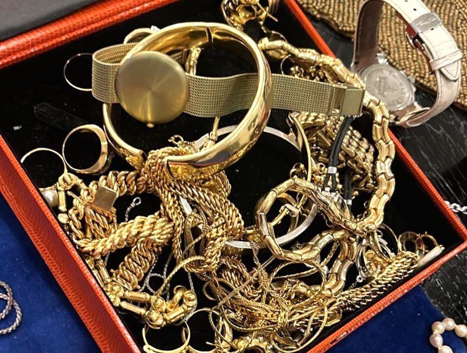Eine Auslage mit goldfarbenem Schmuck sowie Uhren in einer offenen Schmuckschatulle