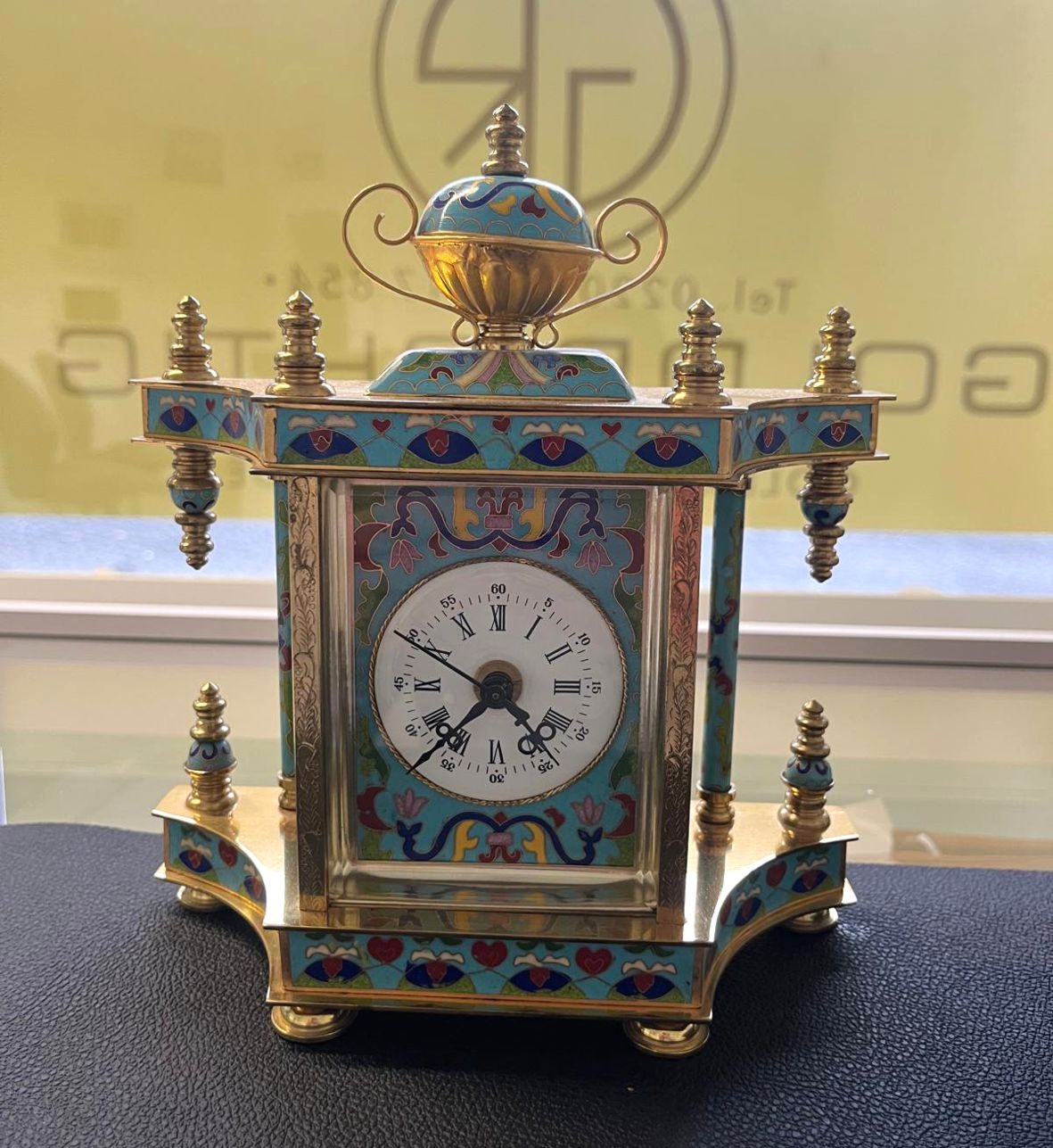 Eine antike Standuhr mit reich verzierten goldenen und bunten Elementen auf schwarzem Untergrund