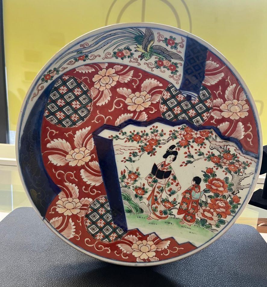 Eine japanische Porzellanplatte mit rotem und blauem Muster und asiatischen Figuren in traditionellen Gewändern