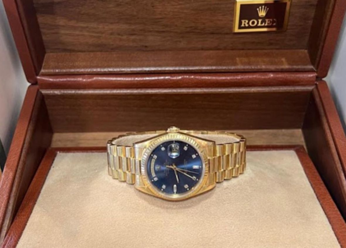 Eine goldene Armbanduhr mit blauem Zifferblatt liegt in einer Rolex Holzbox