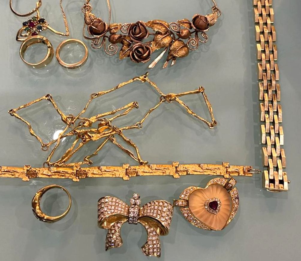 Mehrere goldene Schmuckstücke, darunter Ringe, Ketten und Broschen mit Edelsteinen